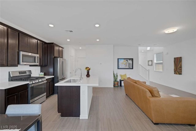 9827 Mojave Mountain St, Las Vegas, NV 89166 - kitchen with stainless steel appliances, open floor plan, dark brown cabinets, light wood finished floors, and recessed lighting