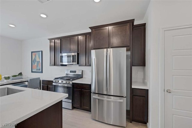 9827 Mojave Mountain St, Las Vegas, NV 89166 - kitchen with appliances with stainless steel finishes, dark brown cabinets, light countertops, recessed lighting, and light wood-style floors
