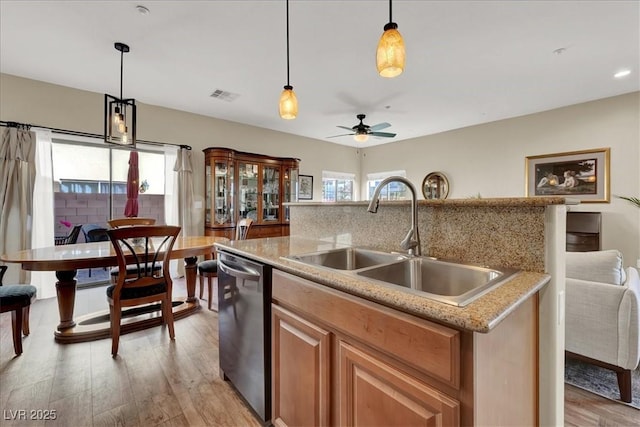 9916 Fallowdeer Ct, Las Vegas, NV 89149 - kitchen featuring a kitchen island with sink, light wood finished floors, stainless steel dishwasher, a ceiling fan, and decorative light fixtures