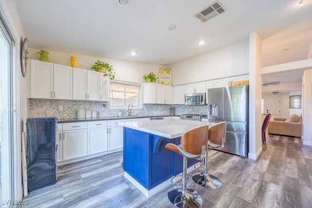 7824 Indian Cloud Ave, Las Vegas, NV 89129 - kitchen with stainless steel appliances, white cabinets, light wood-style floors, a center island, and recessed lighting
