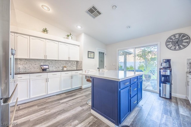 7824 Indian Cloud Ave, Las Vegas, NV 89129 - kitchen featuring lofted ceiling, blue cabinets, white cabinetry, decorative backsplash, and light wood-style flooring