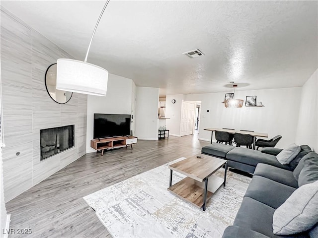 5042 S Rainbow Blvd Unit 103, Las Vegas, NV 89118 - living area with wood finished floors, a tile fireplace, and a textured ceiling