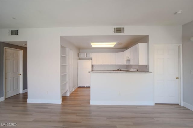 9580 W Reno Ave Unit 240, Las Vegas, NV 89148 - kitchen featuring freestanding refrigerator, white cabinets, a peninsula, and light wood finished floors