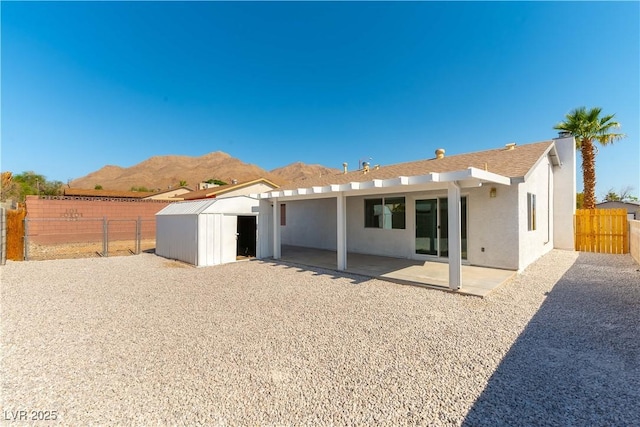 6760 Fallona Ave, Las Vegas, NV 89156 - rear view of house featuring a storage unit, stucco siding, a patio, a mountain view, and a fenced backyard