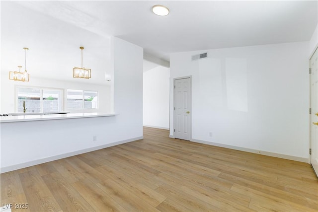 6760 Fallona Ave, Las Vegas, NV 89156 - unfurnished living room with a chandelier, light wood-style flooring, and lofted ceiling