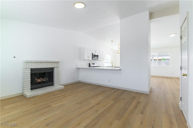 6760 Fallona Ave, Las Vegas, NV 89156 - unfurnished living room featuring light wood finished floors, a fireplace, and vaulted ceiling