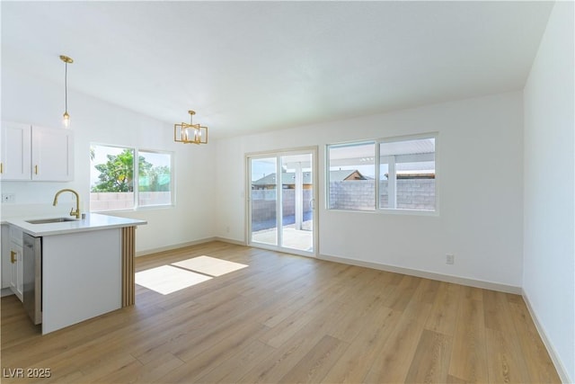 6760 Fallona Ave, Las Vegas, NV 89156 - kitchen featuring light wood-type flooring, a chandelier, light countertops, white cabinetry, and pendant lighting