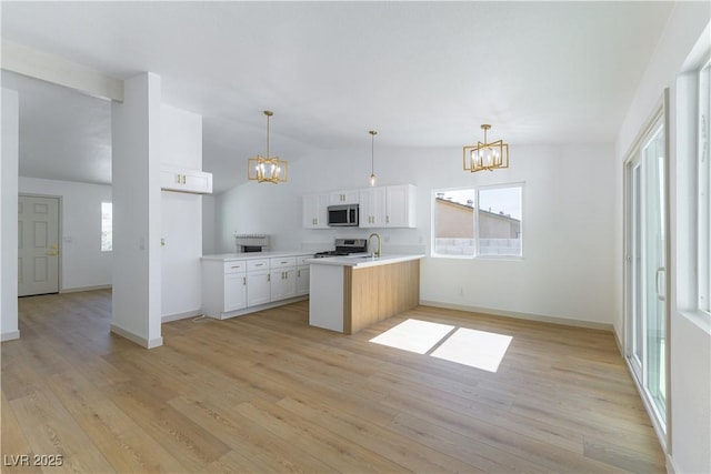 6760 Fallona Ave, Las Vegas, NV 89156 - kitchen with a chandelier, a peninsula, lofted ceiling, white cabinetry, and appliances with stainless steel finishes