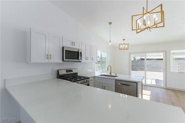6760 Fallona Ave, Las Vegas, NV 89156 - kitchen with a chandelier, a peninsula, stainless steel appliances, light wood finished floors, and hanging light fixtures
