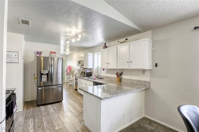 729 Concrete Ct, Las Vegas, NV 89110 - kitchen featuring a textured ceiling, stainless steel appliances, white cabinetry, a peninsula, and light stone countertops