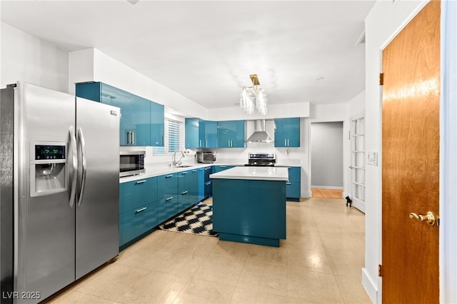 639 Lacy Ln, Las Vegas, NV 89107 - kitchen featuring blue cabinetry, stainless steel appliances, a center island, light countertops, and wall chimney exhaust hood
