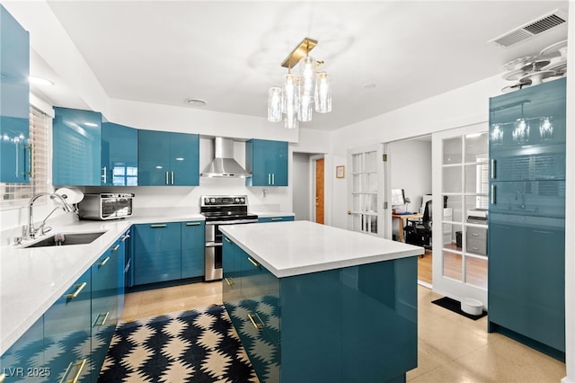 639 Lacy Ln, Las Vegas, NV 89107 - kitchen with blue cabinetry, stainless steel electric range oven, wall chimney exhaust hood, and light countertops
