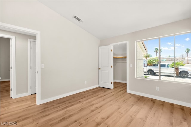 1904 Leaning Pine Way, Las Vegas, NV 89128 - unfurnished bedroom featuring light wood finished floors, lofted ceiling, and a walk in closet