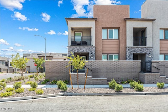 906 Cadence View Way, Henderson, NV 89011 - contemporary house with stucco siding, a fenced front yard, stone siding, a residential view, and a balcony