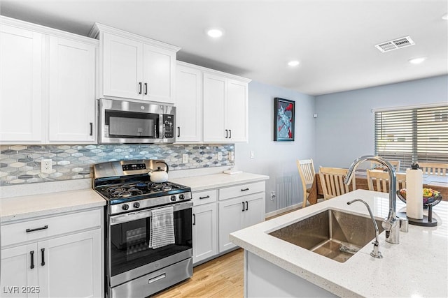 906 Cadence View Way, Henderson, NV 89011 - kitchen with appliances with stainless steel finishes, backsplash, white cabinetry, light wood finished floors, and recessed lighting