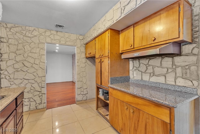 4709 Alpine Pl, Las Vegas, NV 89107 - kitchen with light tile patterned floors, brown cabinetry, and light stone counters
