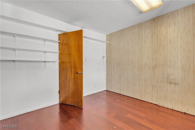 4709 Alpine Pl, Las Vegas, NV 89107 - unfurnished bedroom featuring wood finished floors, wooden walls, a textured ceiling, and a closet