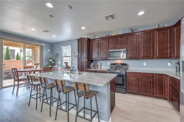 8104 Switchback Run St, Las Vegas, NV 89166 - kitchen with range with gas cooktop, stainless steel microwave, light wood finished floors, light stone counters, and recessed lighting