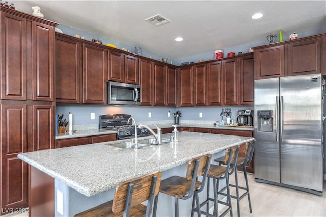 8104 Switchback Run St, Las Vegas, NV 89166 - kitchen with appliances with stainless steel finishes, a kitchen breakfast bar, a kitchen island with sink, light stone counters, and recessed lighting