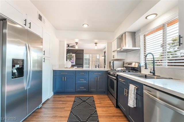 1467 Hialeah Dr Unit C, Las Vegas, NV 89119 - kitchen featuring stainless steel appliances, wall chimney exhaust hood, light countertops, white cabinetry, and recessed lighting