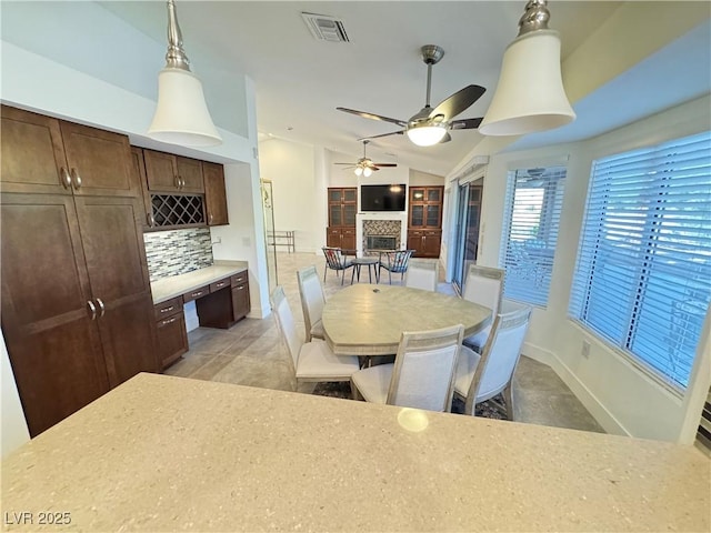 2406 Showcase Dr, Las Vegas, NV 89134 - dining area featuring lofted ceiling, a stone fireplace, ceiling fan, and light tile patterned flooring