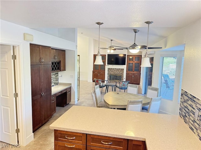 2406 Showcase Dr, Las Vegas, NV 89134 - kitchen with vaulted ceiling, tasteful backsplash, a tile fireplace, a ceiling fan, and light countertops
