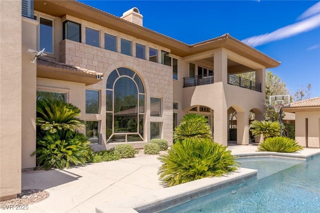 9801 Orient Express Ct, Las Vegas, NV 89145 - rear view of property featuring a balcony, stucco siding, a chimney, and an outdoor pool