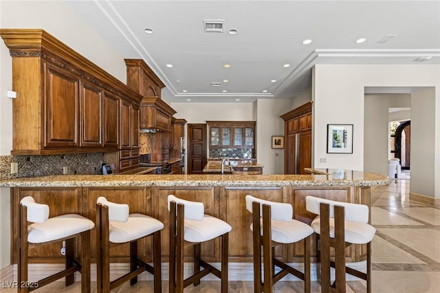 9801 Orient Express Ct, Las Vegas, NV 89145 - kitchen with inlaid floor details, recessed lighting, light stone countertops, decorative backsplash, and a peninsula