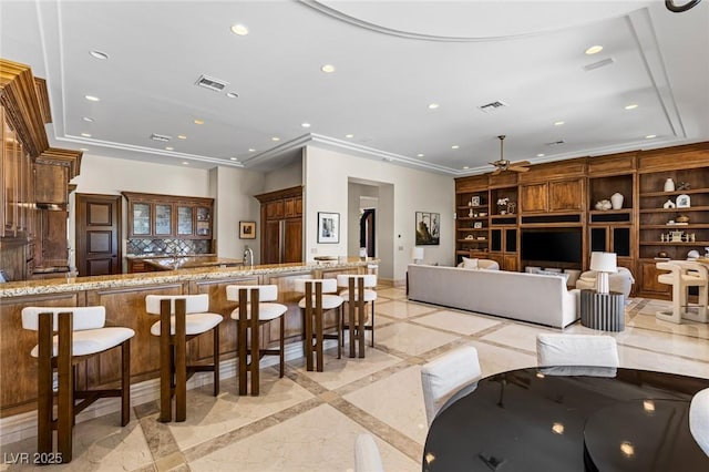 9801 Orient Express Ct, Las Vegas, NV 89145 - kitchen featuring recessed lighting, a breakfast bar area, light stone countertops, ceiling fan, and inlaid floor details