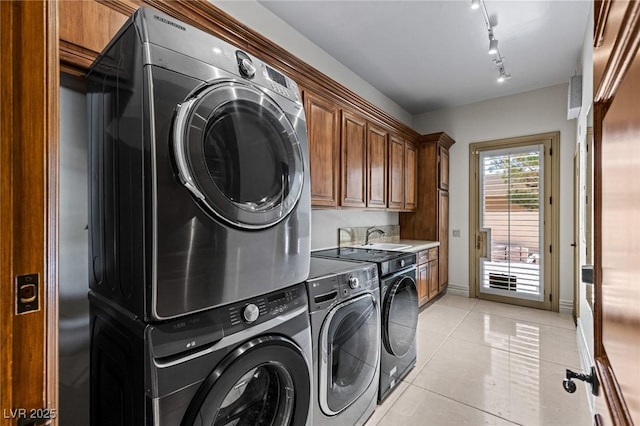 9801 Orient Express Ct, Las Vegas, NV 89145 - laundry area featuring stacked washer / dryer, light tile patterned floors, rail lighting, and cabinet space
