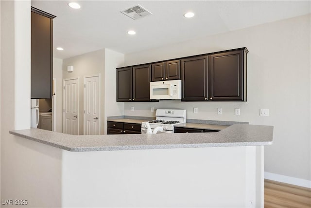 2563 Sargon St, Henderson, NV 89044 - kitchen with white appliances, light countertops, dark brown cabinetry, recessed lighting, and a peninsula