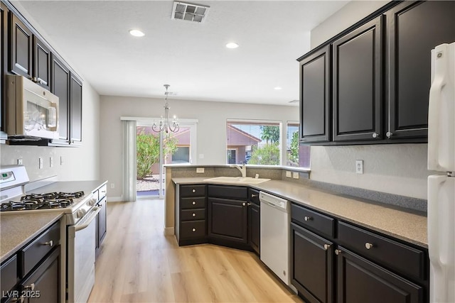 2563 Sargon St, Henderson, NV 89044 - kitchen featuring white appliances, light wood finished floors, recessed lighting, a chandelier, and pendant lighting