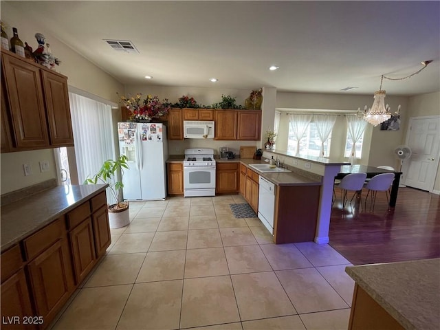 5625 Fast Payout Ct, Las Vegas, NV 89122 - kitchen with white appliances, a peninsula, a chandelier, brown cabinets, and recessed lighting
