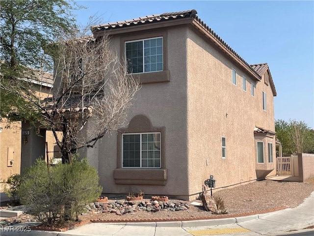 5625 Fast Payout Ct, Las Vegas, NV 89122 - view of side of home with stucco siding, a tile roof, and a gate