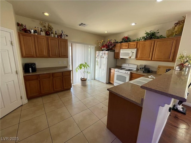 5625 Fast Payout Ct, Las Vegas, NV 89122 - kitchen with white appliances, brown cabinetry, a peninsula, recessed lighting, and a breakfast bar