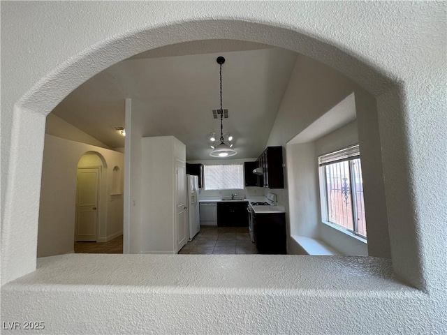 2503 River Oaks Dr, Las Vegas, NV 89156 - kitchen with vaulted ceiling, light countertops, plenty of natural light, white appliances, and arched walkways