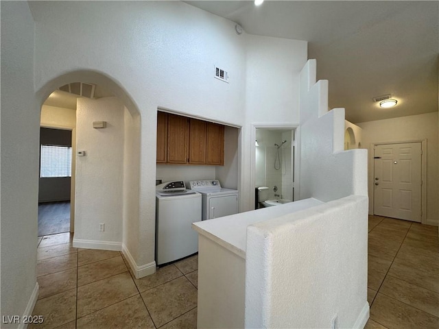 2503 River Oaks Dr, Las Vegas, NV 89156 - laundry area featuring arched walkways, light tile patterned floors, washing machine and clothes dryer, a high ceiling, and cabinet space