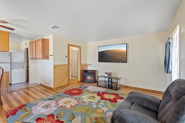 1481 Lorilyn Ave Unit 1, Las Vegas, NV 89119 - living area featuring stacked washer / dryer, light wood-type flooring, a glass covered fireplace, a ceiling fan, and wainscoting