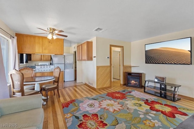 1481 Lorilyn Ave Unit 1, Las Vegas, NV 89119 - living area featuring light wood-style floors, a glass covered fireplace, a ceiling fan, wainscoting, and wooden walls