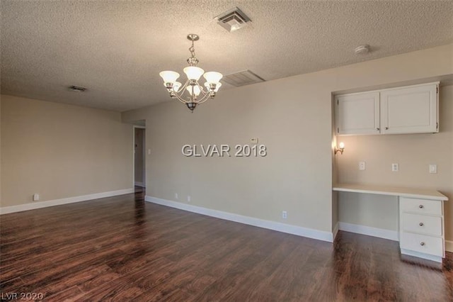 empty room with dark hardwood / wood-style flooring, a textured ceiling, and a chandelier