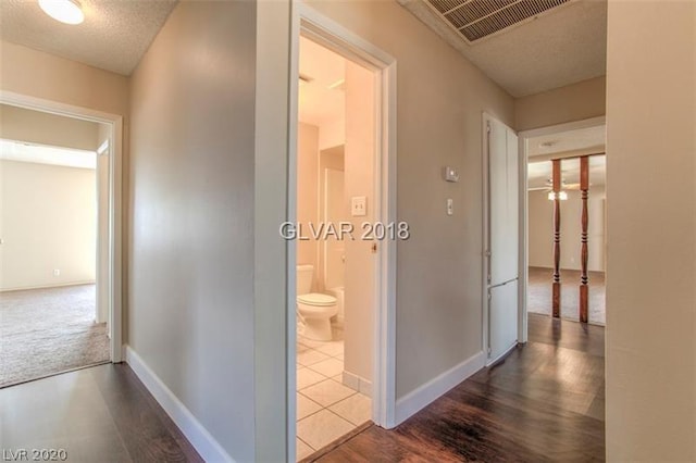 hall featuring dark colored carpet and a textured ceiling