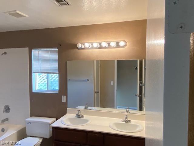 full bathroom with double sink vanity, toilet, and shower / bathing tub combination