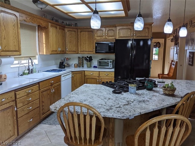 kitchen featuring pendant lighting, a kitchen breakfast bar, light tile floors, black appliances, and sink