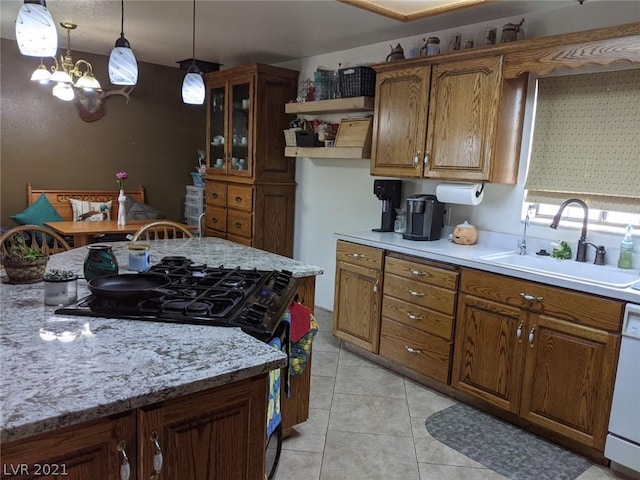 kitchen with a notable chandelier, sink, light tile floors, light stone counters, and pendant lighting