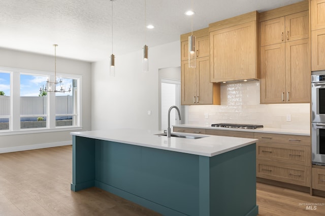 1351 E Andes Dr, Kuna, ID 83634 - kitchen with a sink, backsplash, an island with sink, light countertops, and light wood-style flooring