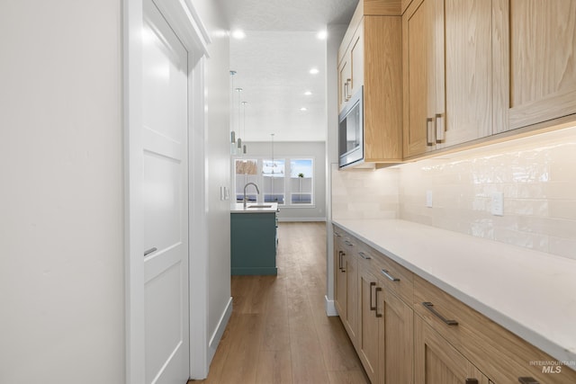 1351 E Andes Dr, Kuna, ID 83634 - kitchen featuring light wood-style flooring, light countertops, stainless steel microwave, a sink, and light brown cabinets