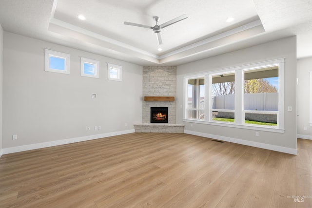 1351 E Andes Dr, Kuna, ID 83634 - unfurnished living room featuring a tray ceiling, light wood finished floors, ceiling fan, a stone fireplace, and recessed lighting