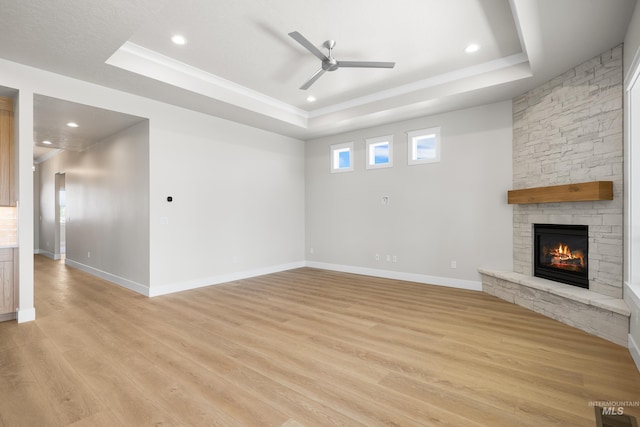 1351 E Andes Dr, Kuna, ID 83634 - unfurnished living room with a tray ceiling, a stone fireplace, ceiling fan, light wood-type flooring, and recessed lighting