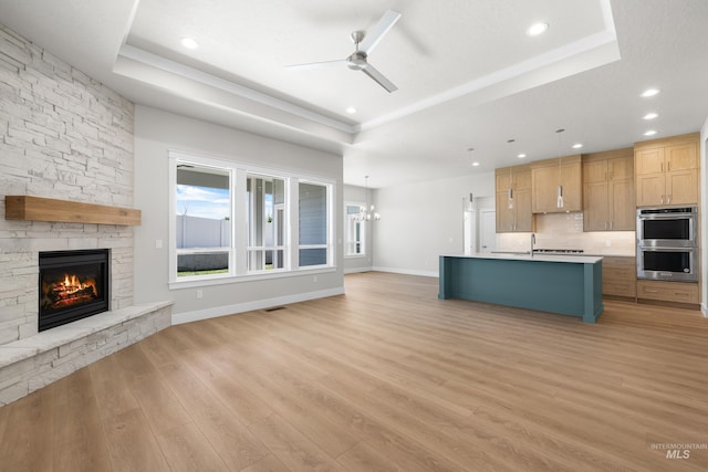 1351 E Andes Dr, Kuna, ID 83634 - unfurnished living room with a tray ceiling, a fireplace, a ceiling fan, healthy amount of natural light, and recessed lighting