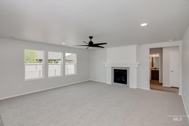 unfurnished living room featuring a tile fireplace, light colored carpet, and ceiling fan